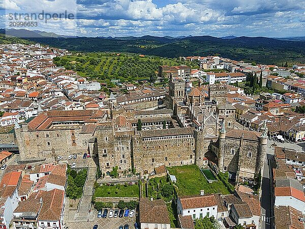 Aerial view of an old monastery with red roofs and surrounding green areas in a village in Spain. Historic architecture and scenic beauty. Aerial view  pilgrimage church and monastery  Real Monasterio de Nuestra Señora de Guadalupe  Guadalupe  Cáceres province  Caceres  Extremadura  Spain  Europe