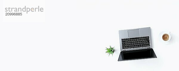 Top view above on gray thin isolated laptop notebook  white cup of espresso coffee  green flowerpot with houseplant on the white background. Banner with copy space for advertisement text