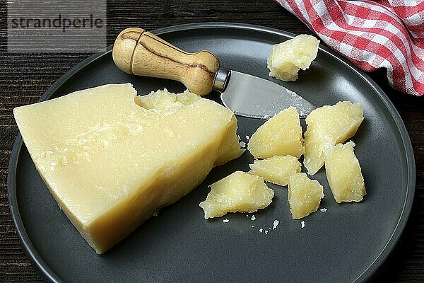 A piece of Parmesan cheese and chopped pieces of cheese on a plate