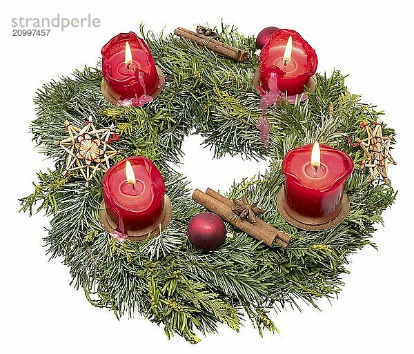 View from above of an ornate Advent wreath made of fir branches with burning red candles set free on white