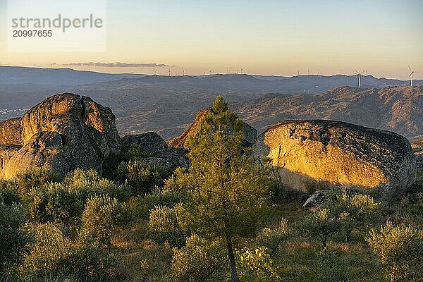 Sortelha nature landscape view with mountains  trees  boulders and wind turbines at sunset  in Portugal