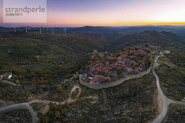 Drone aerial panorama of Sortelha historic village at sunset with lights on the castle eolic wind turbines and nature landscape  in Portugal