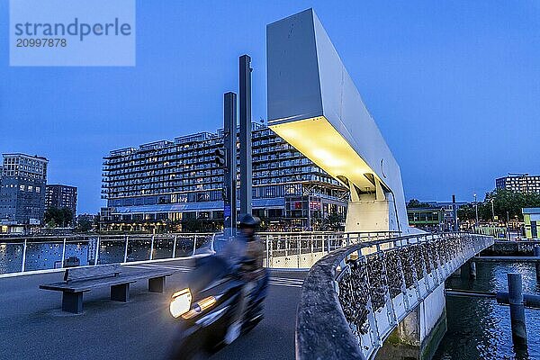 The former Fenix warehouse  left  from 1923  destroyed in the war  renovated in 2019  converted into a residential and commercial building  with hotel  flats  restaurants  offices  warehouses  on the Rijnhaven harbour basin  Rijnhavenbrug  bridge  Rotterdam  Netherlands