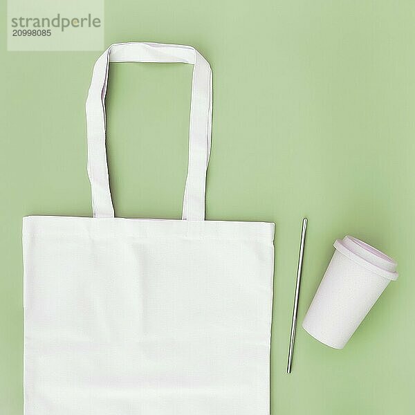 Eco white craft paper bag  metal drink straw  coffee cup on green background flat lay with copy space empty advertising area. Mock up for delivery service  reusable and recyclable resources concept