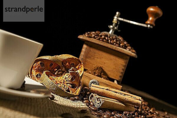 Close-up on dried orange fruit and cinnamon sticks with coffee grinder and black background