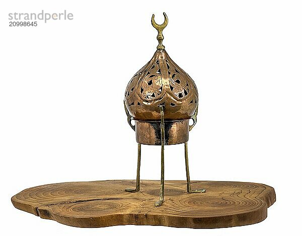 Old oriental incense burner made of copper stands on a wooden disc  isolated on white