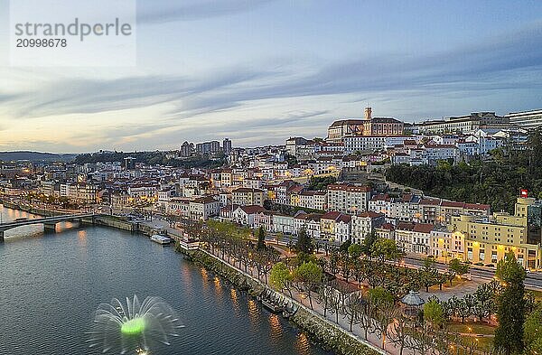 Coimbra drone aerial city view at sunset with colorful fountain in Mondego river and beautiful historic buildings  in Portugal