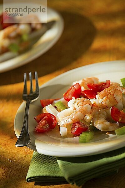 Shrimp salad with squid tomatoes and celery over a green napkin with an orange background