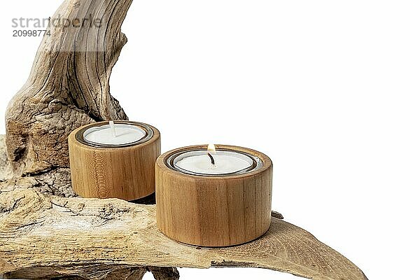 Burning tea light stands on a light-coloured tree root  isolated on white as decoration