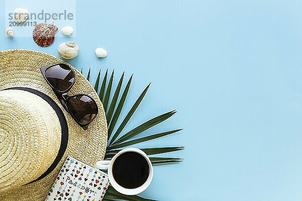 Travel  vacation concept. Hat with sea shells  palm leaf  passport  eyeglasses and cup of coffee on blue background.