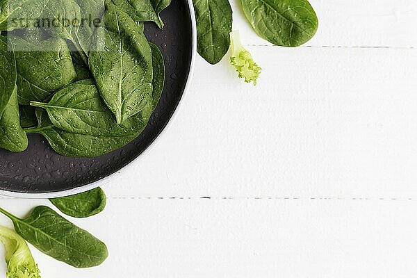 Bowl with fresh green salad leaves  spinach  lettuce  basil on a white background. Healthy vegetarian eating concept.