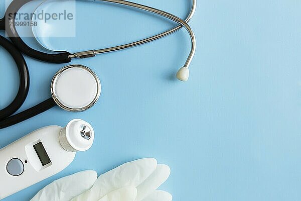 Medicine treatment concept. Electronic thermometer  phonendoscope or stethoscope  white gloves on blue background.