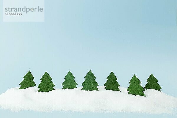 Green christmas trees on blue background with fake snow