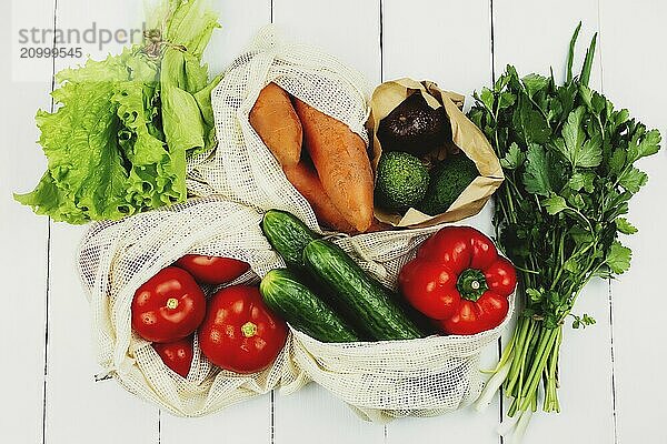 Fresh vegetables in eco bags on white table.