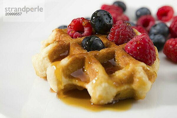 Close-up of waffles with fresh ripe berries on a white background