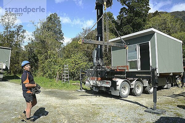 GREYMOUTH  NEW ZEALAND  OCTOBER 21  2020: A crane operator works on lifting a small building from a truck onto its pilings