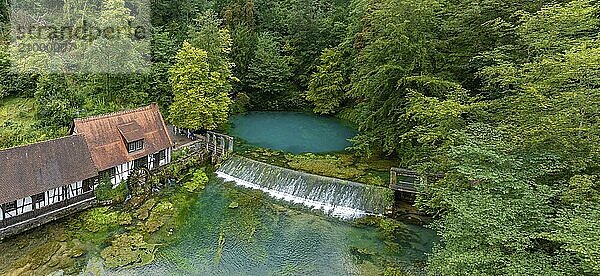 Blautopf Blaubeuren with industrial monument Hammerschmiede  source of the little river Blau in a landscape with forest. Karst spring  geotope and geopoint of the UNESCO Swabian Alb Geopark  tourist attraction. The popular excursion destination is now being thoroughly renovated and will therefore be closed to visitors until the end of 2028. Drone photo. Blaubeuren  Baden-Württemberg  Germany  Europe