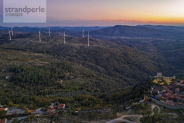 Drone aerial panorama of Sortelha historic village at sunset with lights on the castle eolic wind turbines and nature landscape  in Portugal