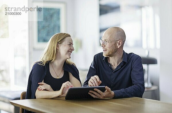 Symbolic photo. A woman and a man sit together at a table with a tablet and talk. Berlin  13.08.2024