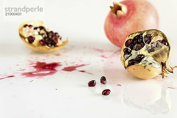 Half pomegranate and juice on white background