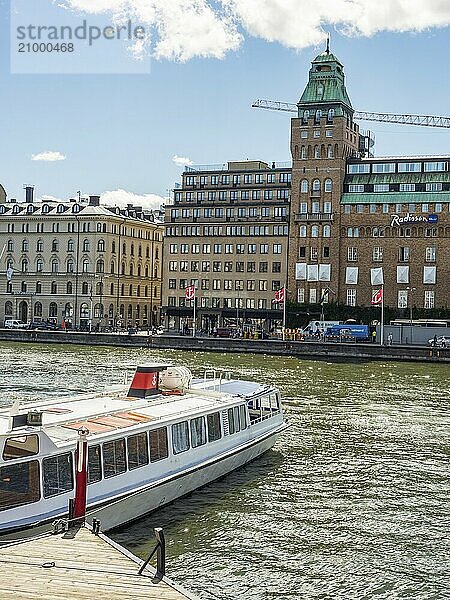 City scene with several large buildings and boats on the water in sunny weather  stockholm  baltic sea  sweden  scandinavia