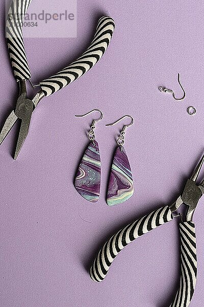 Purple  blue and teal earrings on purple background with tools