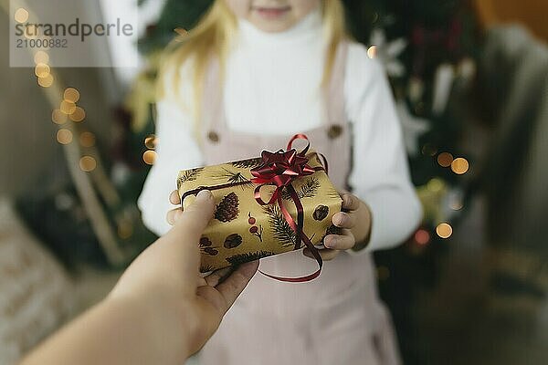 Christmas gift in hands  giving gift at home  little girl receiving a christmas present  girl holding a christmas gift.