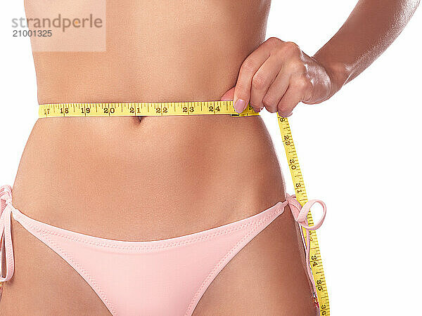 Young woman measuring her waist with a measuring tape  closeup of stomach isolated on white background