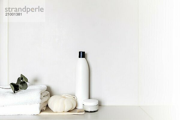 White bathroom shelf with different bath accessories. Hotel cleaning concept. Household concept. Washcloth  shampoo  cream  plant  toothbrush  brush  eucalyptus leaves on white towels. Body  skin care