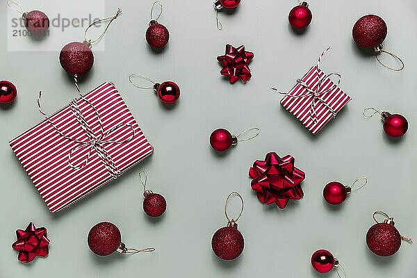 Gray background with two pink Christmas gift box presents  small red Christmas balls or sphere toys  ribbon bows for fir tree. Concept for festive sales  promotions  greeting card or invitation photo