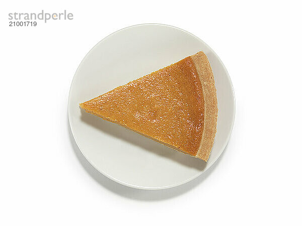 Piece of a pumpkin pie on a saucer isolated on white background with a clipping path