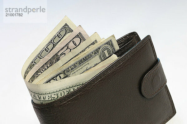 Brown leather wallet with US dollar bills sticking out of it Isolated on white