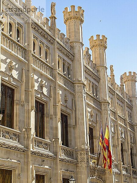 Side view of a magnificent historic building  decorated with sculptures and flags  in Gothic style under a blue sky  palma de Majorca  mallorca  balearic islands  spain