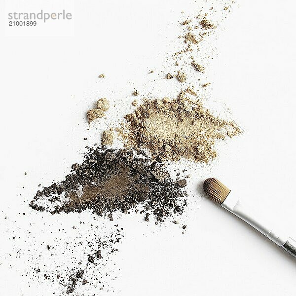 Scattered light and dark brown face shadow and eye shadow or make-up brush. Makeup concept flat lay on white background