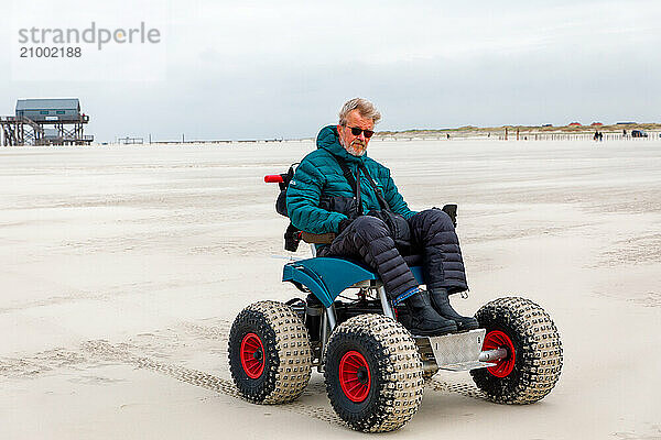 Man with handicap on the beach with a beach wheelchair  Sankt-Peter-Ording  Schleswig-Holstein