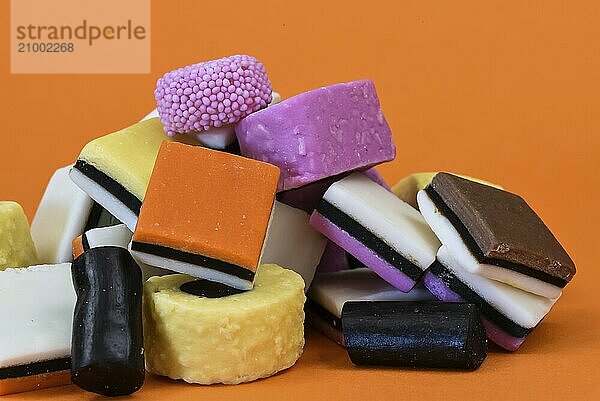 Den Helder  the Netherlands. January 2022. Various types of English licorice in different colors against an orange background.