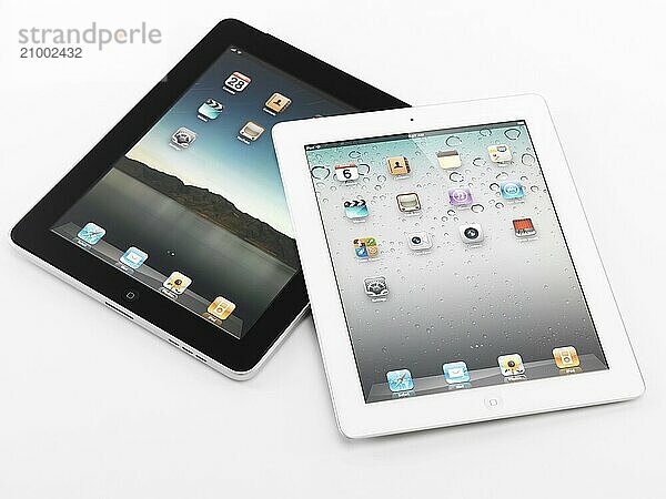 White Apple iPad 2 and black iPad tablet computers. Isolated on white background