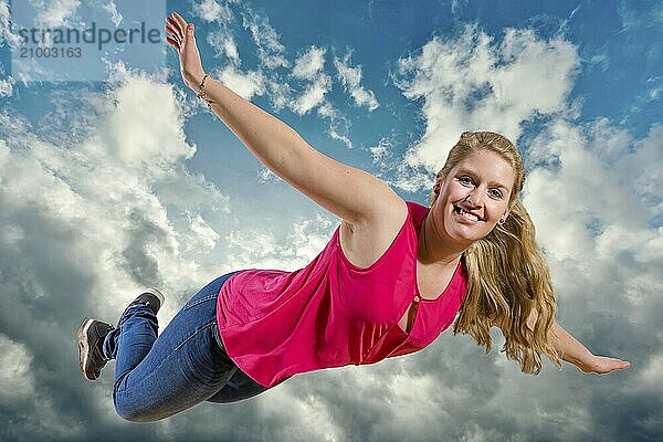 Young girl flies laughing high in clouds against a blue sky