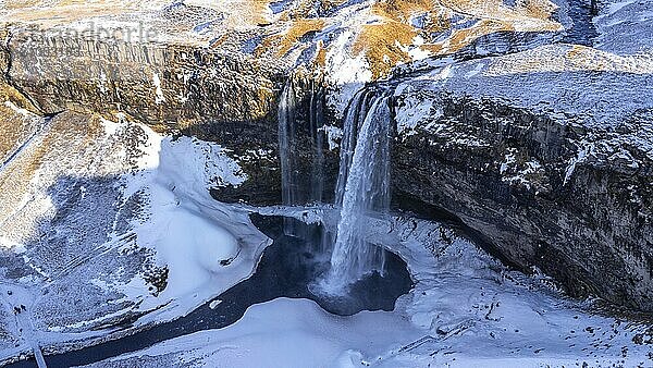 Aerial drone view of frozen Seljalandsfoss waterfall with snow in Iceland