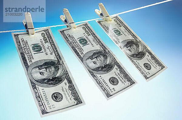 Hundred dollar bills drying on a clothes line isolated on blue sky background Money laundering concept