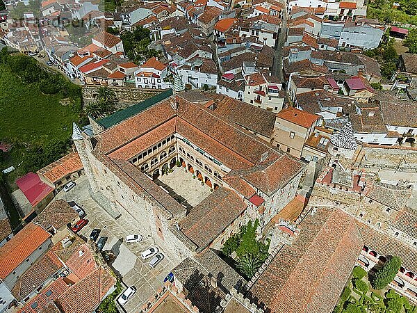 Aerial view of a monastery with a central courtyard and red roofs  surrounded by a village. Historical  medieval architecture in Spain  aerial view  pilgrimage church and monastery  Real Monasterio de Nuestra Señora de Guadalupe  Guadalupe  Cáceres province  Caceres  Extremadura  Spain  Europe