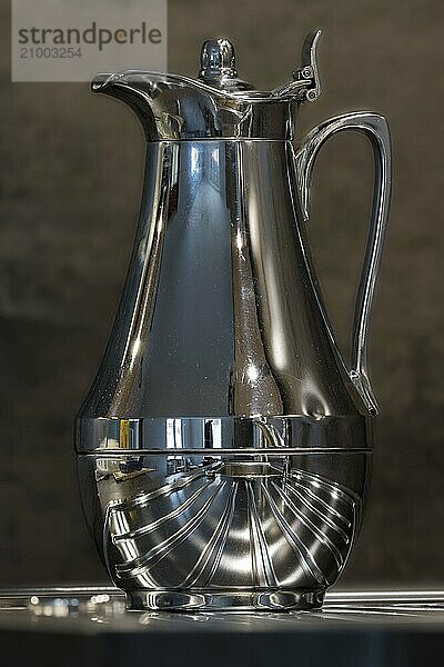 Shiny used coffee pot with strong reflections against a dark background