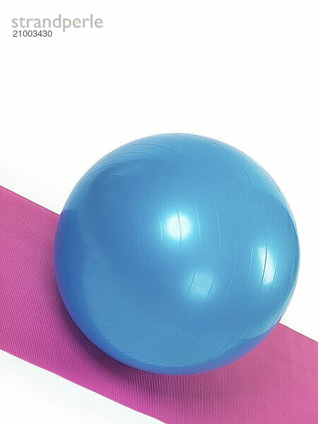 Blue fitness ball on purple mat isolated on white background