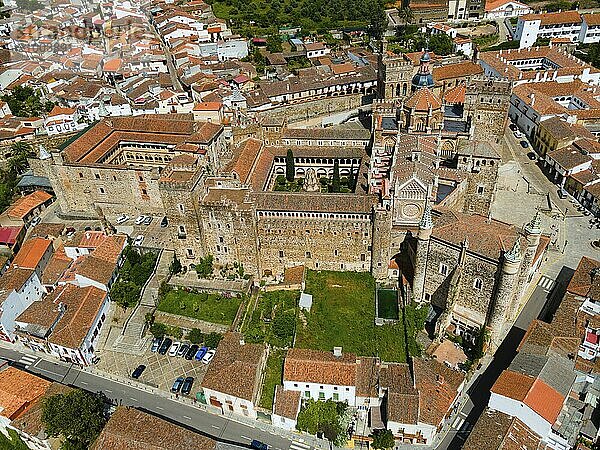 Aerial view of an old monastery with courtyard and red roofs  surrounded by a village in Spain. Historic and medieval architecture. Aerial view  pilgrimage church and monastery  Real Monasterio de Nuestra Señora de Guadalupe  Guadalupe  Cáceres Province  Caceres  Extremadura  Spain  Europe