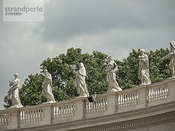 Statues on columns under cloudy sky with green background in classical style in the Vatican  Rome  Italy  Europe