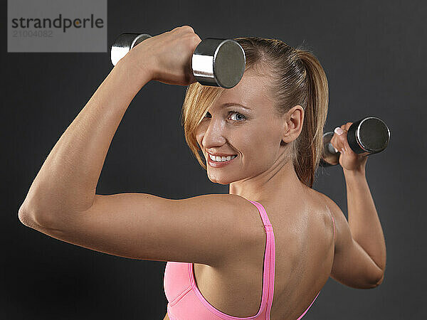 Portrait of a young smiling fitness woman exercising with weights