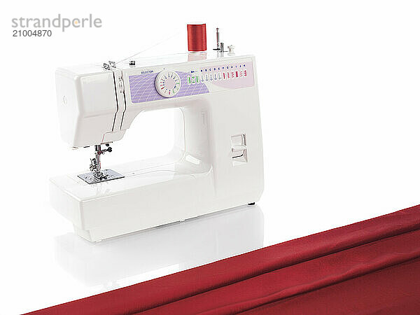 Sewing machine and red fabric isolated on white background