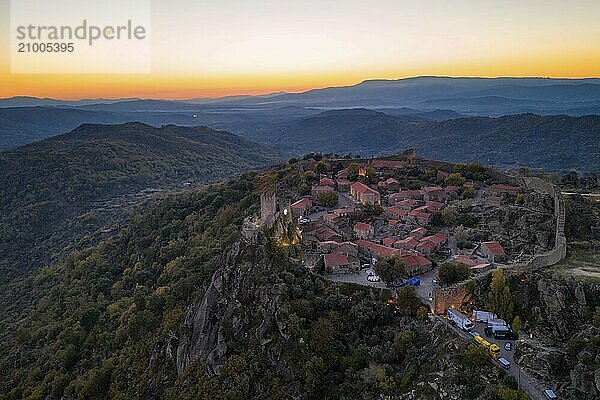 Drone aerial panorama of Sortelha historic village at sunset with lights on the castle eolic wind turbines and nature landscape  in Portugal