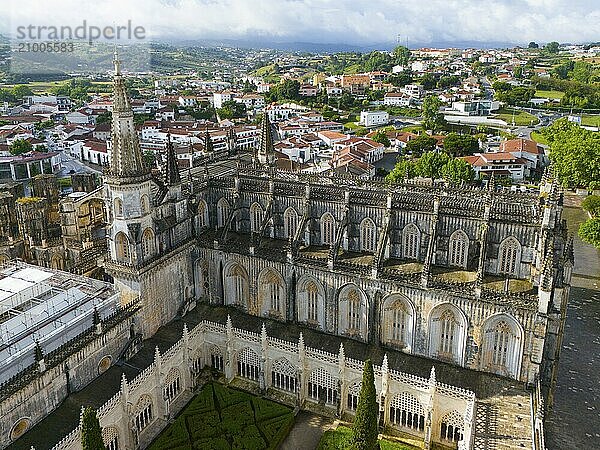 Aerial view of a Gothic cathedral with a tower and detailed windows  embedded in an urban landscape and surrounded by green nature  aerial view  monastery  Mosteiro de Santa Maria da Vitória  'unfinished chapels'  UNESCO World Heritage Site  Batalha  Leiria  Estremadura  Portugal  Europe