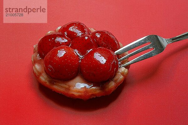 Strawberry tartlet with fork on red background  fruit cake